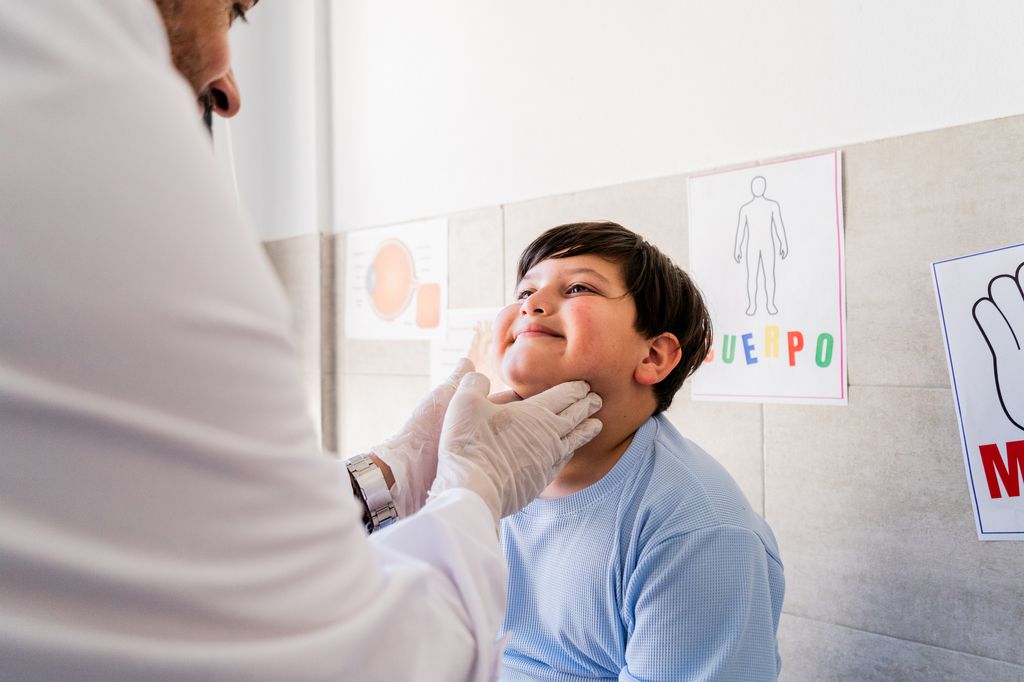 Niño en el médico revisándole la garganta