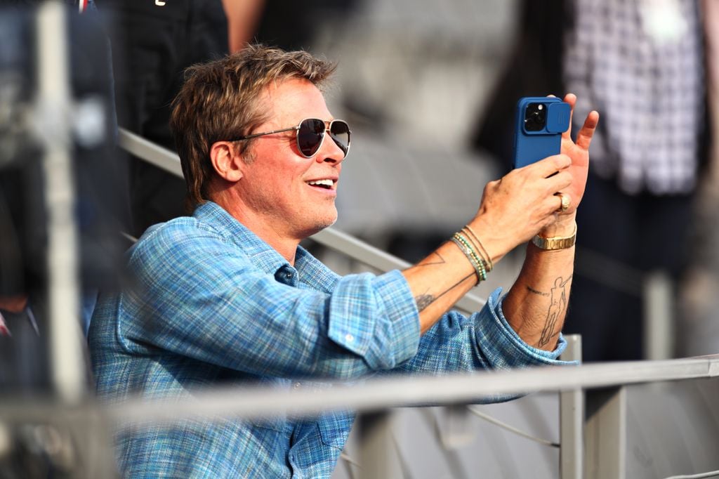 Primer plano de Brad Pitt en el público del Gran Premio de México 2024 haciendo una foto con su móvil