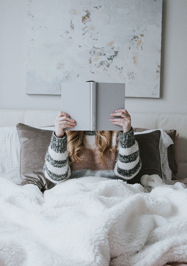 Persona leyendo un libro con una manta en las piernas