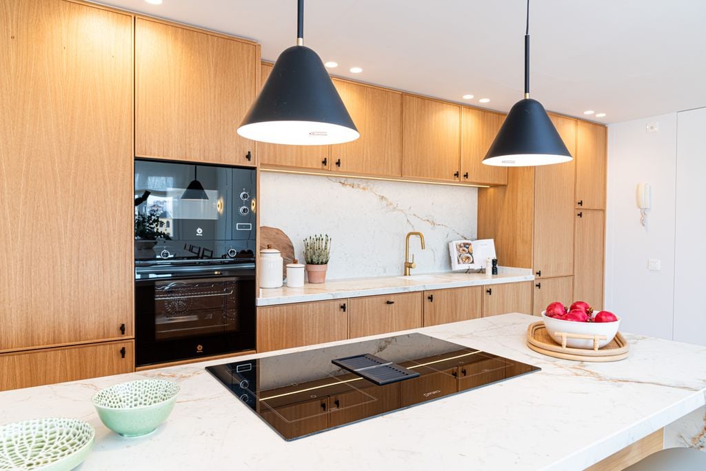 Cocina con las luces encendidas, a base de lámparas colgantes. focos y tiras bajo los armarios