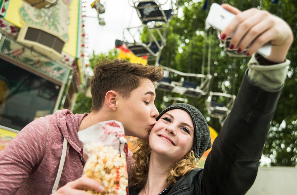 pareja de adolescentes dándose un beso y haciéndose un selfie