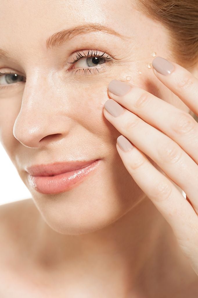 Rostro de mujer aplicándose sérum en el contorno de ojos