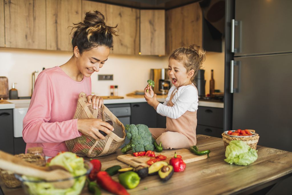 Madre con su hija en la cocina con verduras