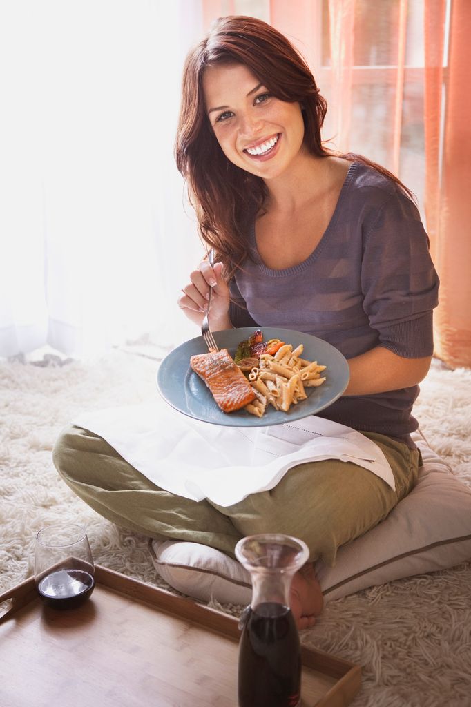 Una mujer comiendo pescado con verduras