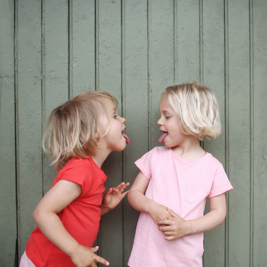 dos niñas gemelas o mellizas jugando juntas, sacando la lengua