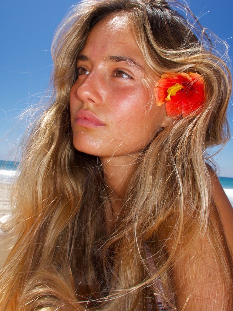 Makayla Storms con el pelo suelto, una flor en el pelo y la piel bronceada