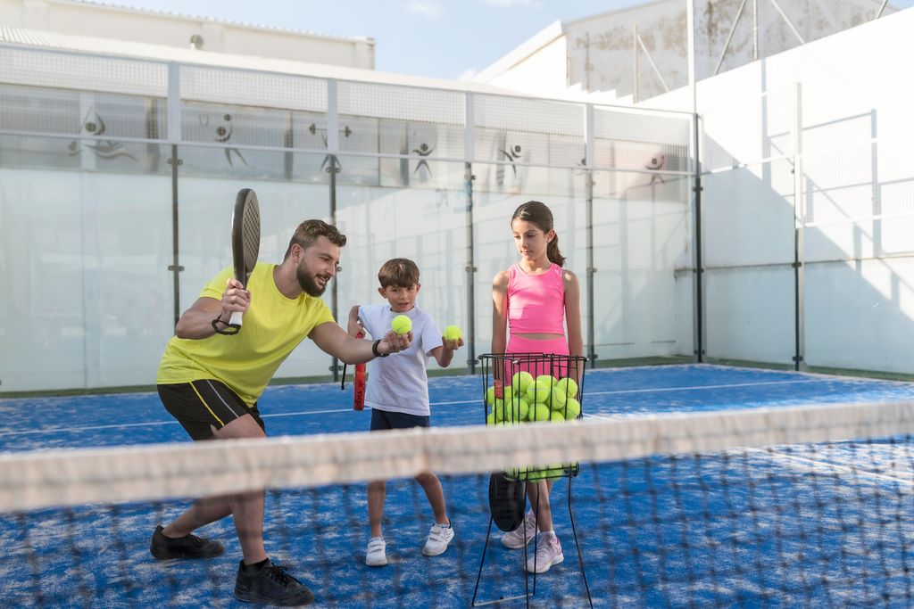 padre con sus hijos enseñándoles a jugar al tenis