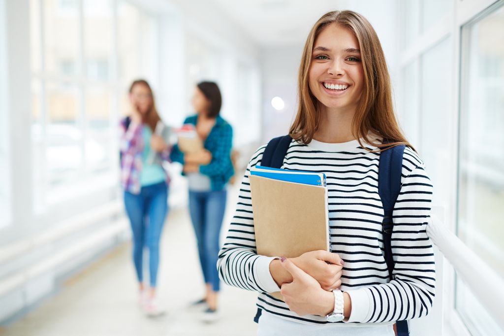 Estudiante universitaria feliz con libros en la mano