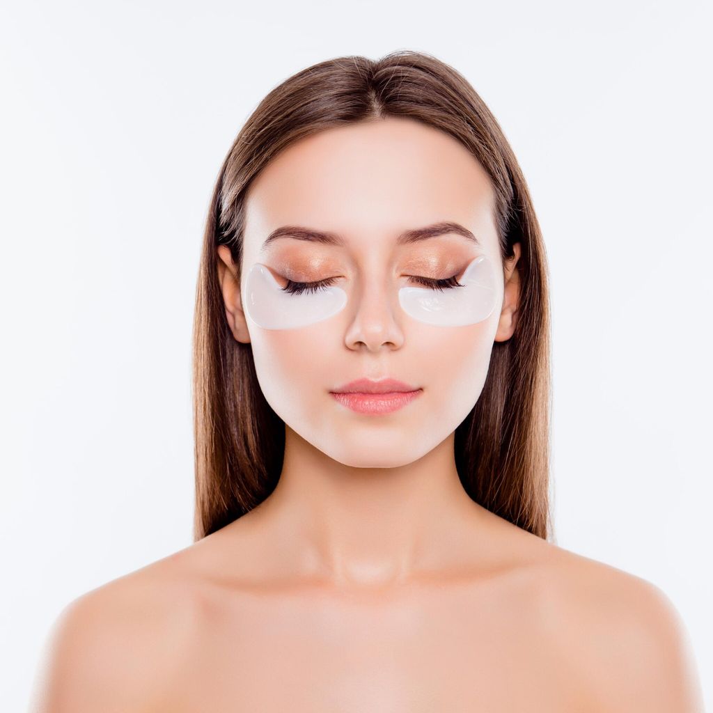 Mujer aplicando parches debajo de sus ojos para atacar las ojeras