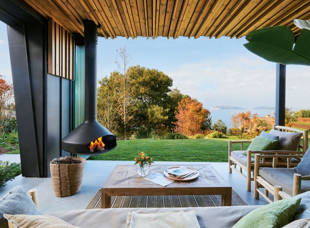 Salón de exterior ideal para disfrutar también cuando bajan las temperaturas, al poderse cerrar y contar con una chimenea