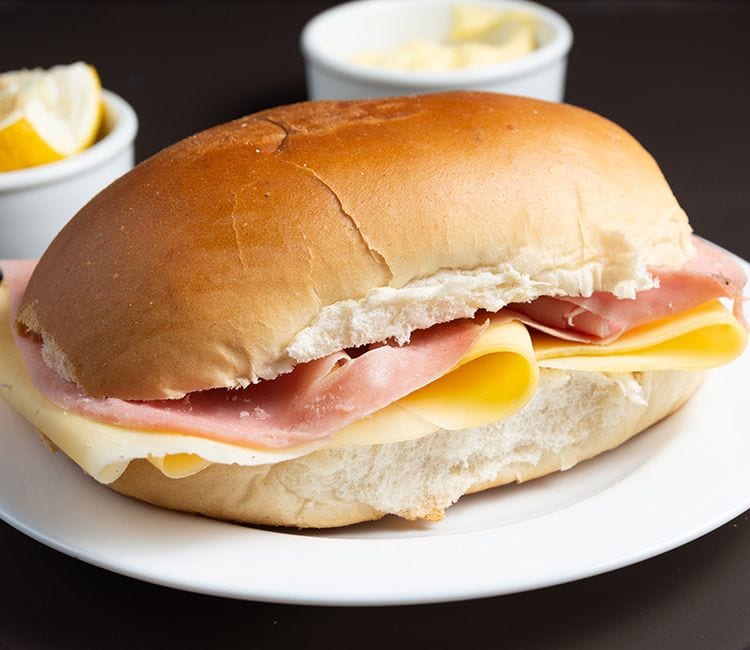 Medianoche rellena de mantequilla, jamón cocido y queso