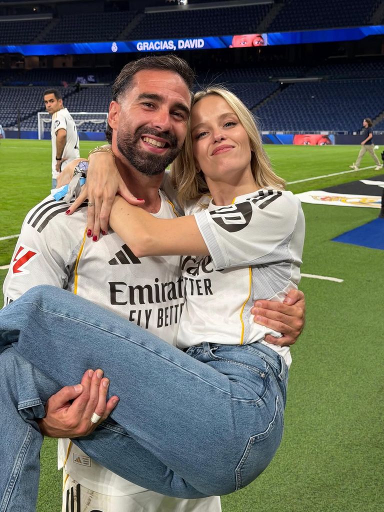 Dani Carvajal sonriendo abraza a una mujer en un estadio de fútbol.