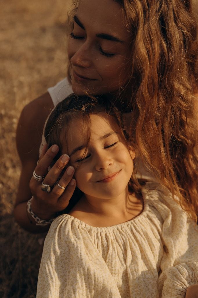 Madre e hija dándose un abrazo en el campo al atardecer