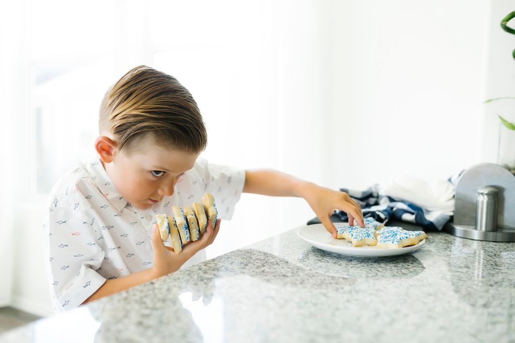 Niño cogiendo todas las galletas de un plato