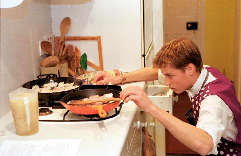 El príncipe William de Inglaterra cocinando una paella de pollo durante una clase de cocina en Eton.