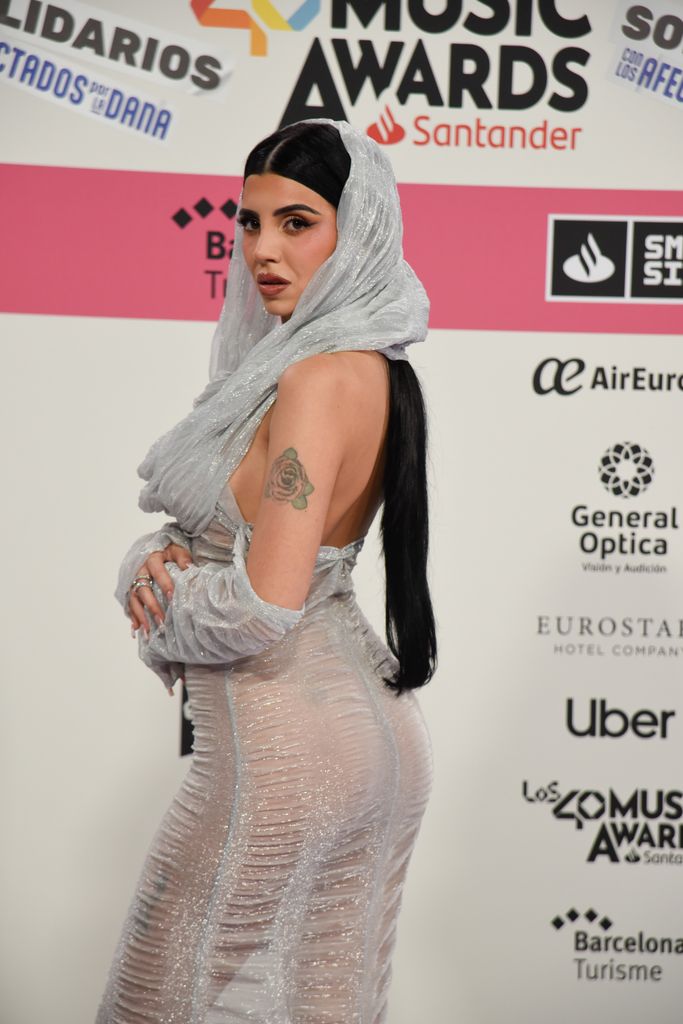 Plano medio de Naiara con vestido plateado de transparencias con capa