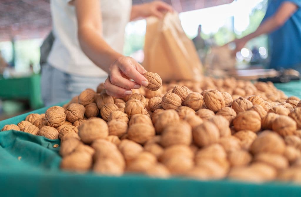 mujer comprando nueces en un supermercado, metiéndolas en una bolsa de papel