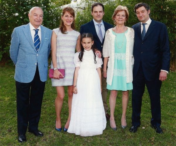 La pequeña Nerea posa sonriente junto a su familia en el día de su primera comunión
