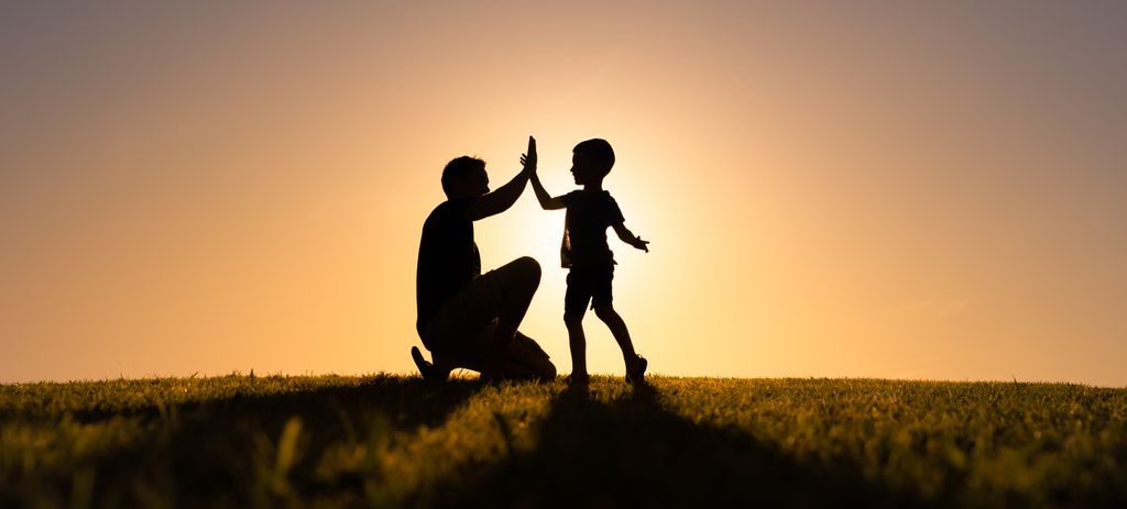 Padre chocando las palmas con su hijo en la naturaleza