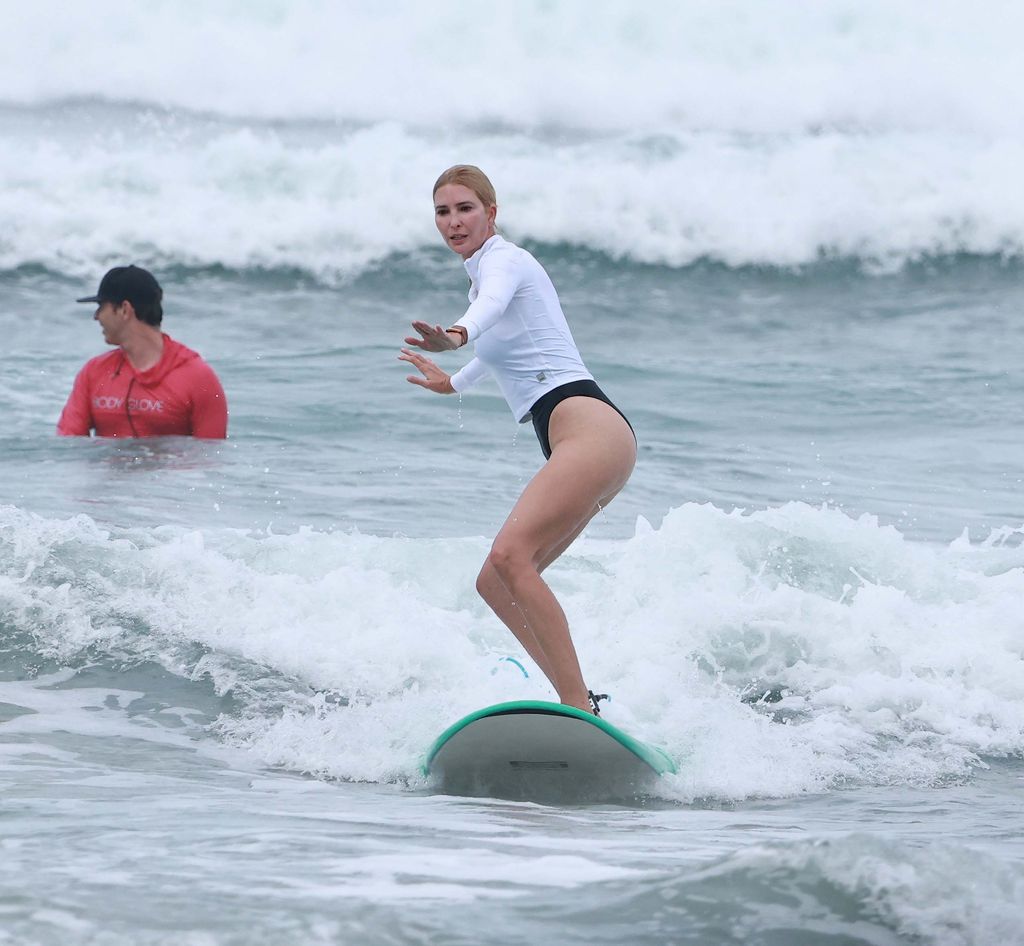 Ivanka Trump fue fotografiada practicando surf durante unas vacaciones familiares, vestida con un top blanco de manga larga y una parte inferior negra mientras utilizaba una tabla azul brillante tipo soft-top longboard. 