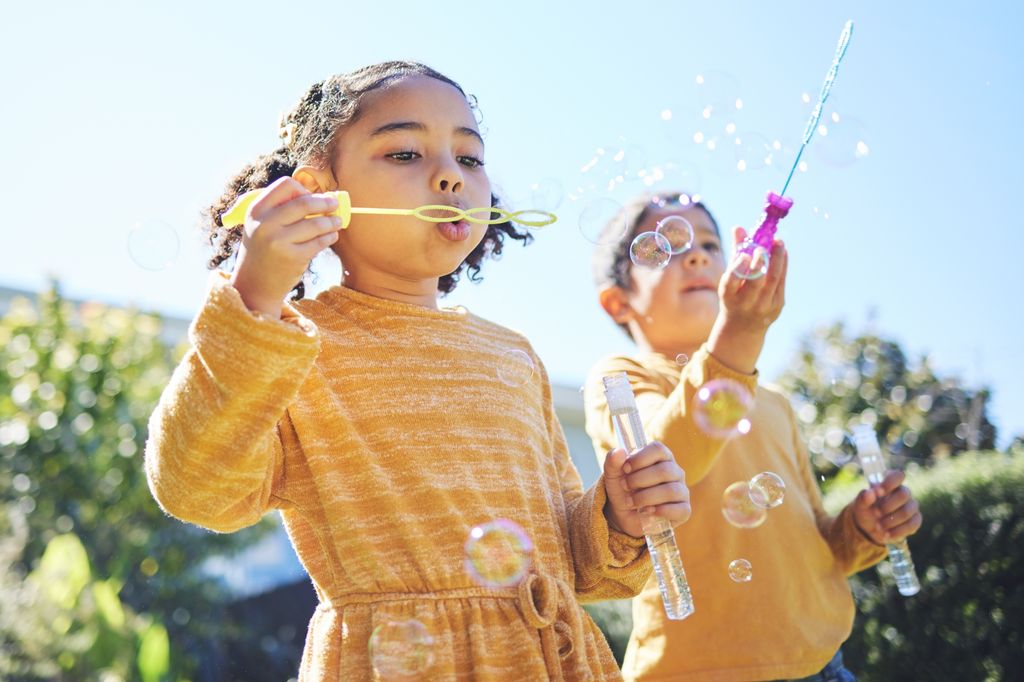 Niños jugando con pompas en el parque
