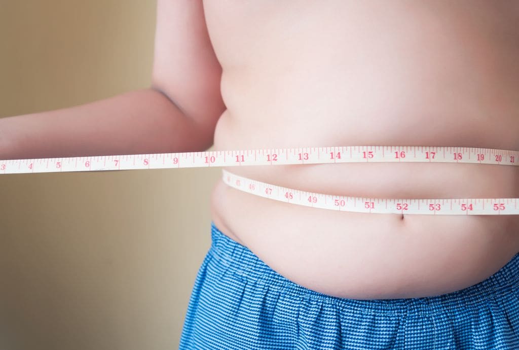 Niño con obesidad con una cinta métrica en el abdomen