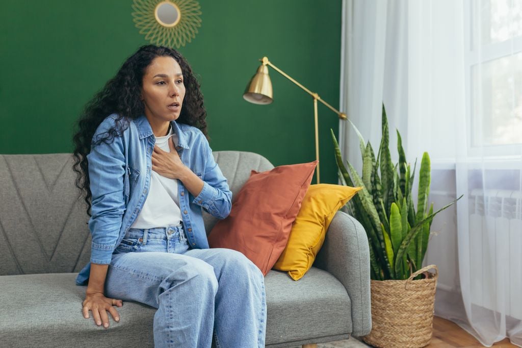 mujer con problemas para respirar de forma correcta, sentada en el sofá