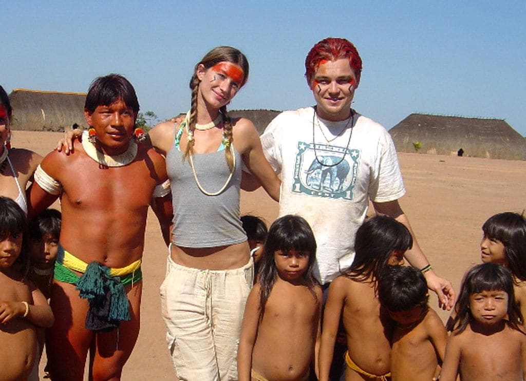 Plano medio de Gisele Bundchen y Leonardo DiCaprio posando con indios en un viaje