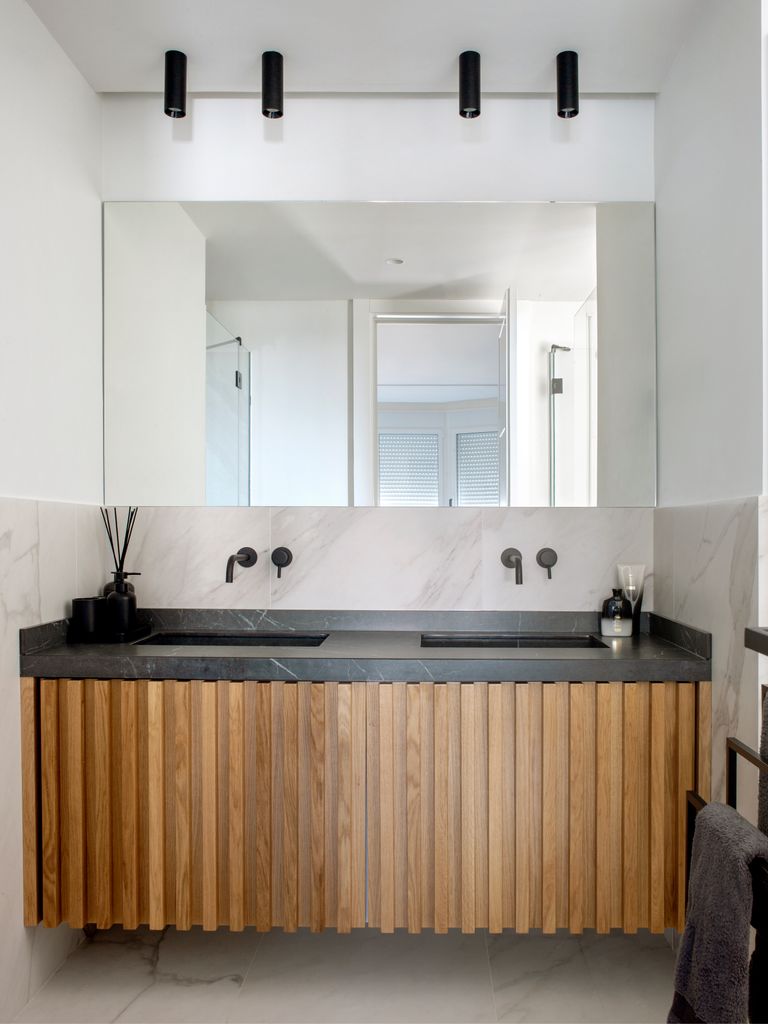 Baño con mueble de madera y luna sin marco en la pared del lavabo