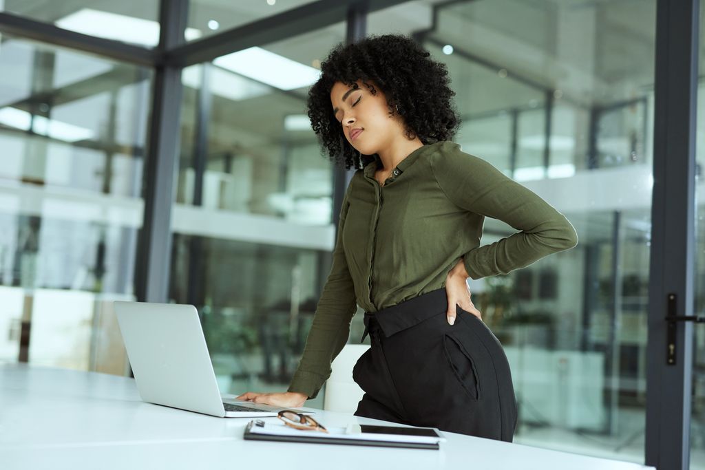 mujer con dolor de espalda en la oficina