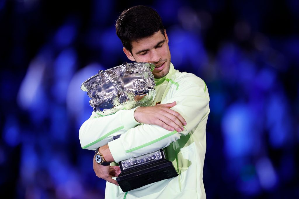 Carlos Alcaraz abrazando la copa ganada por su victoria en el Open de Australia, tras vencer a Novak Djokovic.