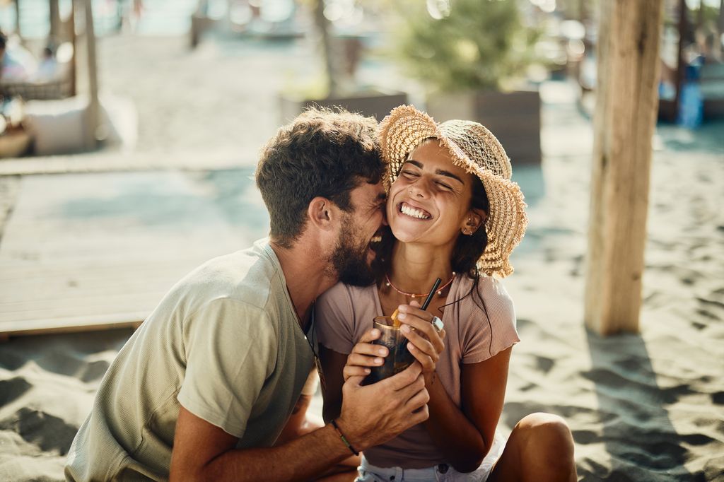 Joven pareja divirtiéndose en la playa 