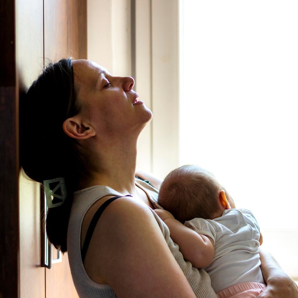 Tired concerned mother rocking sleeping baby.