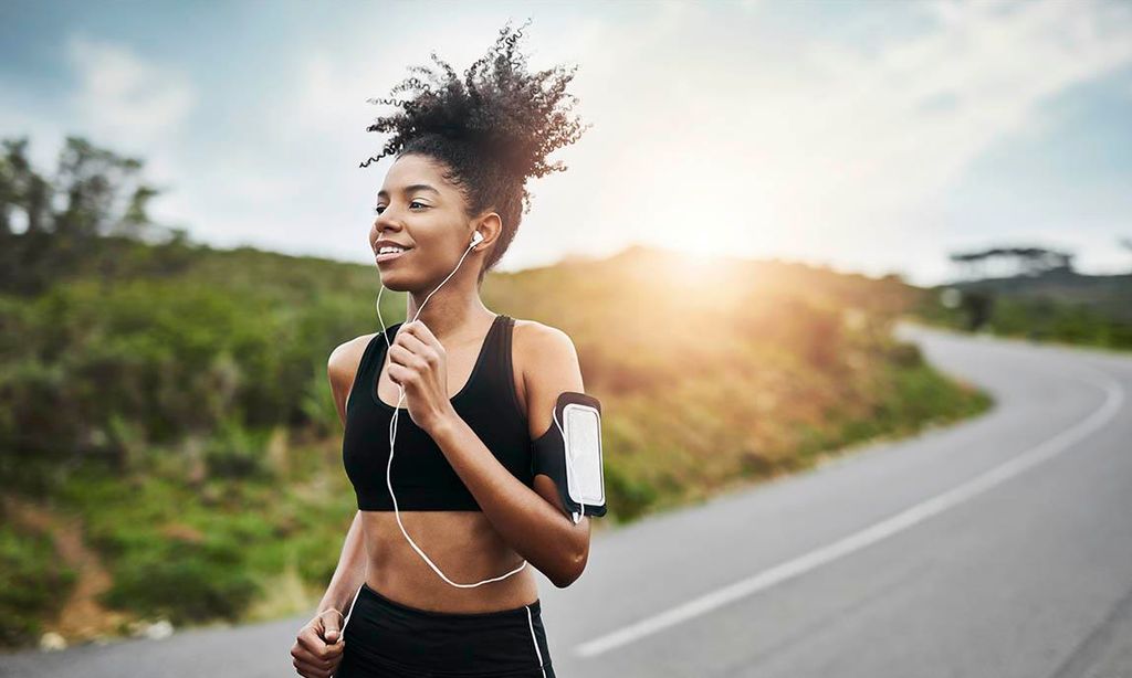 Chica trotando al lado de la carretera y escuchando música