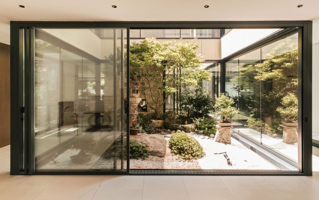 La entrada a la vivienda que recibe con un impresionante jardín japonés interior  