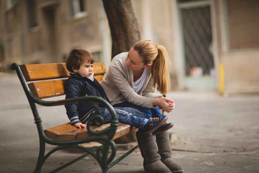 Madre hablando con su hijo pequeño en un banco de la calle