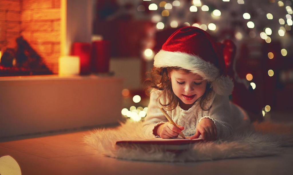 ni a escribiendo carta de reyes magos con gorrito de pap noel