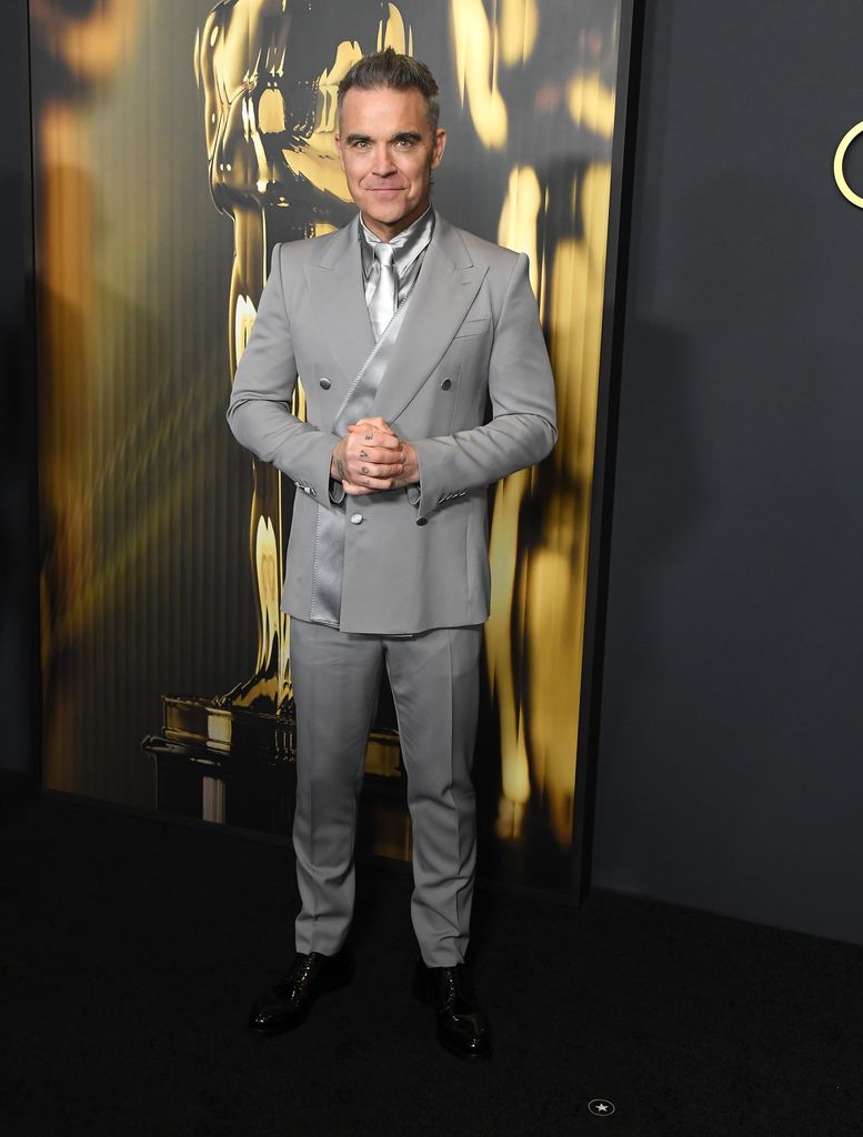 Plano medio de Robbie Williams con traje gris