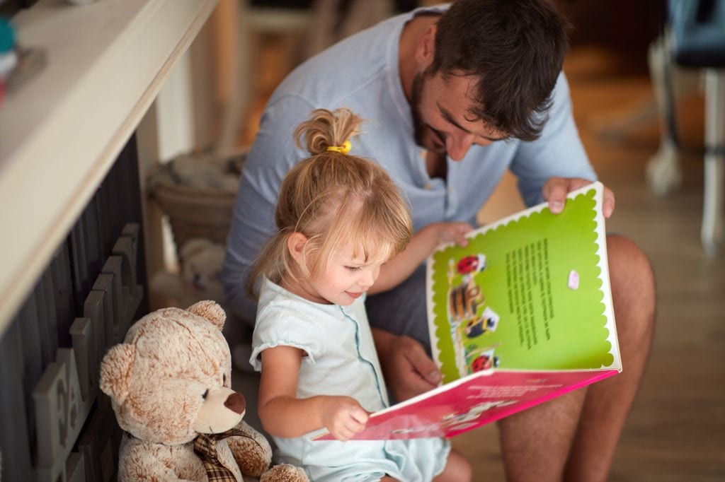 Padre leyendo un libro con su hija pequeña