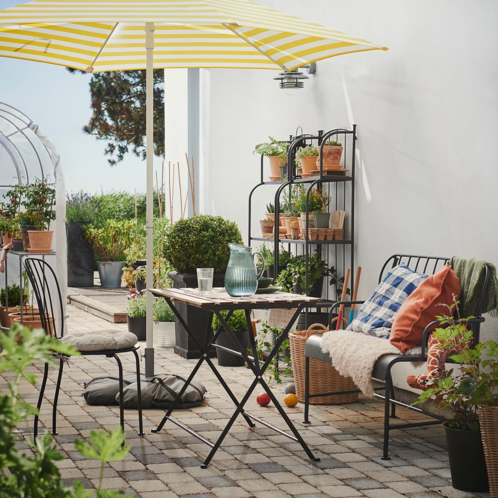 Terraza con un rincón de relax y un mueble que alberga un buen número de plantas