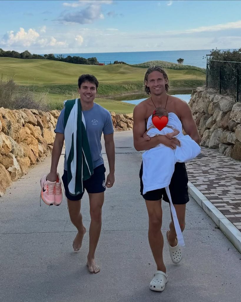 El futbolista, subiendo de la playa con su pequeña en brazos y acompañado por Álex González