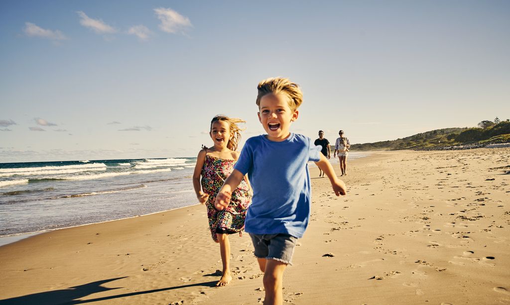 Niños felices de vacaciones corriendo por la playa