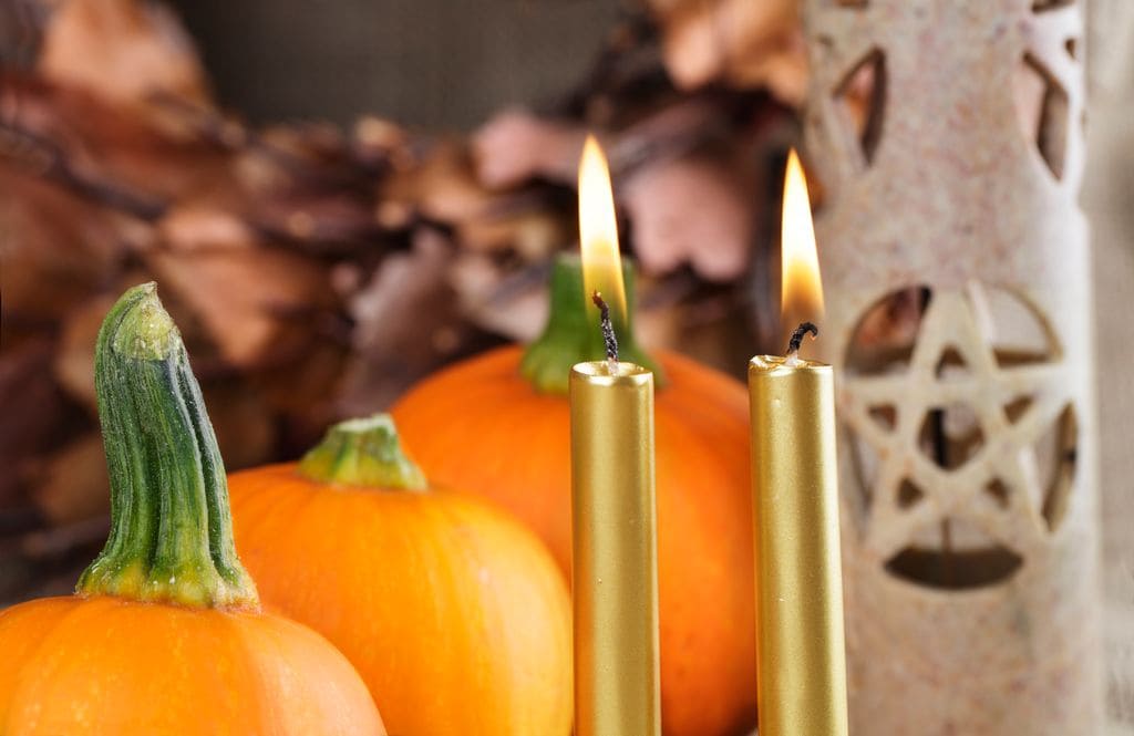 Un altar pagano con velas doradas, preparado para la celebración de Samhain. Esta festividad ancestral, que tiene lugar el 31 de octubre, marca el fin del verano y la cosecha, y es una noche dedicada a honrar a los antepasados