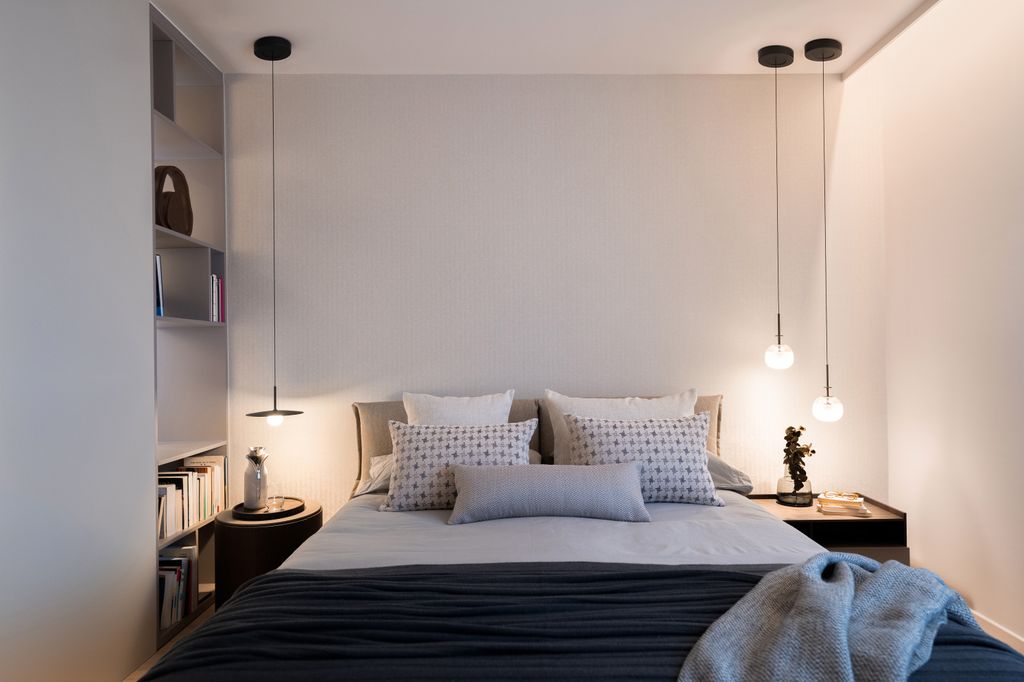Dormitorio con lámparas de suspensión a cada lado de la mesilla