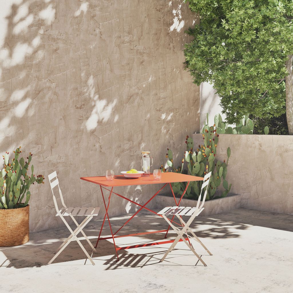 Comedor de verano con muebles plegables en acero, con la mesa en un tono terracota