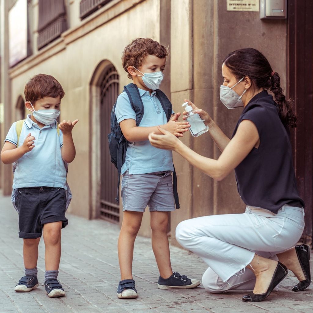 Teacher using hand sanitizer with kids going back to school