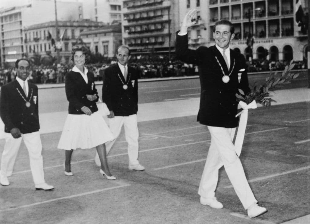 El entonces príncipe heredero Constantino de Grecia, en los Juegos Olímpicos de 1960, en el que quedó campeón de vela, le sigue su hermana, la reina Sofía, entonces princesa y quien le había acompañado en todos los entrenamientos