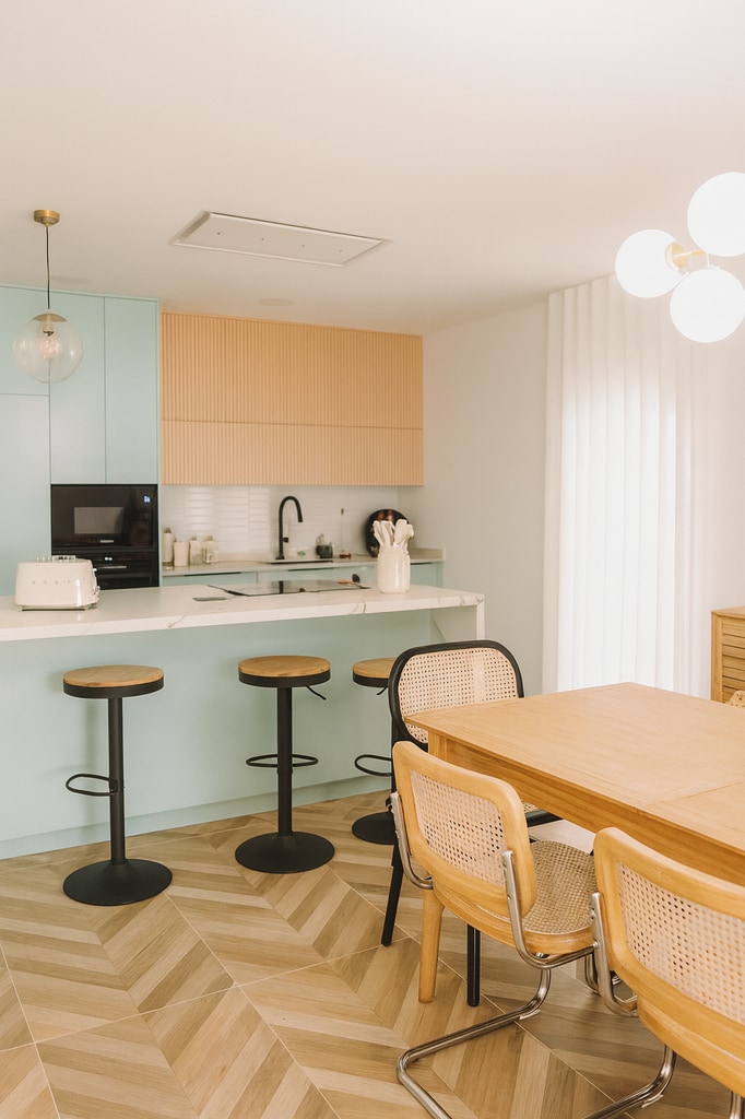 Cocina con toques distintivos: grifería negra, parte del mobiliario en un verde pastel y una iluminación muy bien estudiada