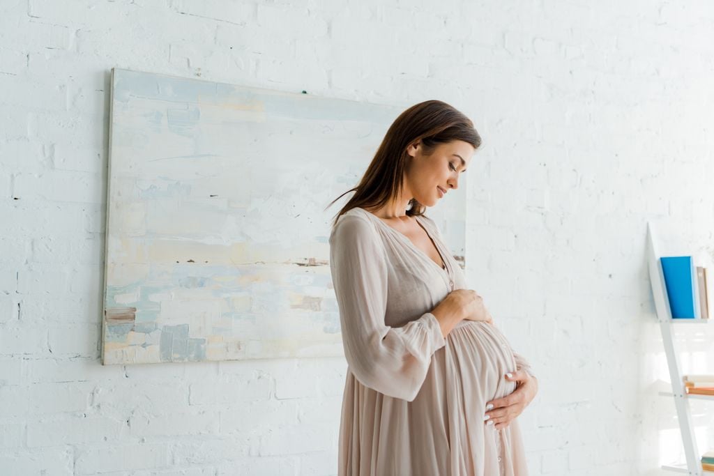Embarazada tocándose la barriga con actitud tierna