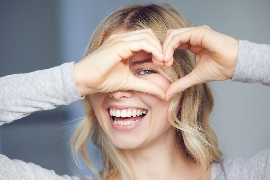 Mujer haciendo un corazón y sonriendo